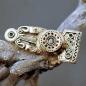 Preview: Vendelzeitliche Rückenknopffibel  aus Bronze von Gotland auf einem Ast